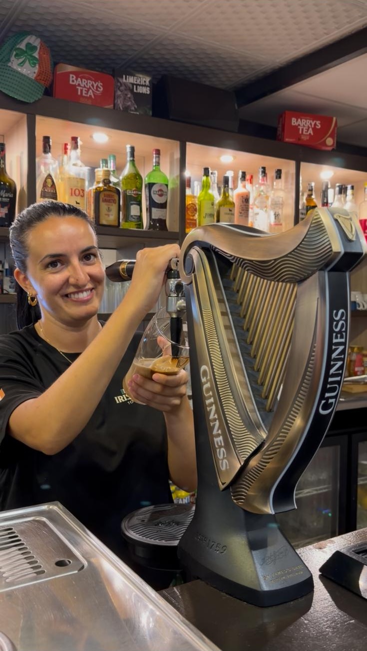 Staff member pouring a pint of Guinness at the harp tap