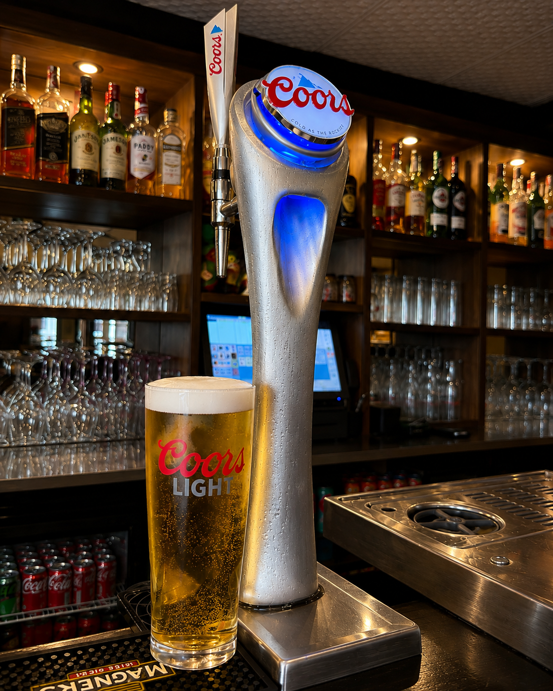 Freshly poured pint of Coors Light beside the Coors tap at the bar